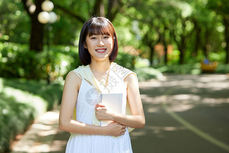 女生刘海室外女生抱着书本散步背景