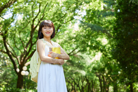 金秀贤户外写真室外女生拿着书本散步背景