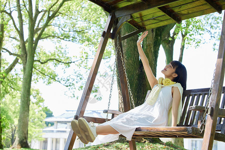 荡秋千的少女夏日清爽美女享受阳光背景