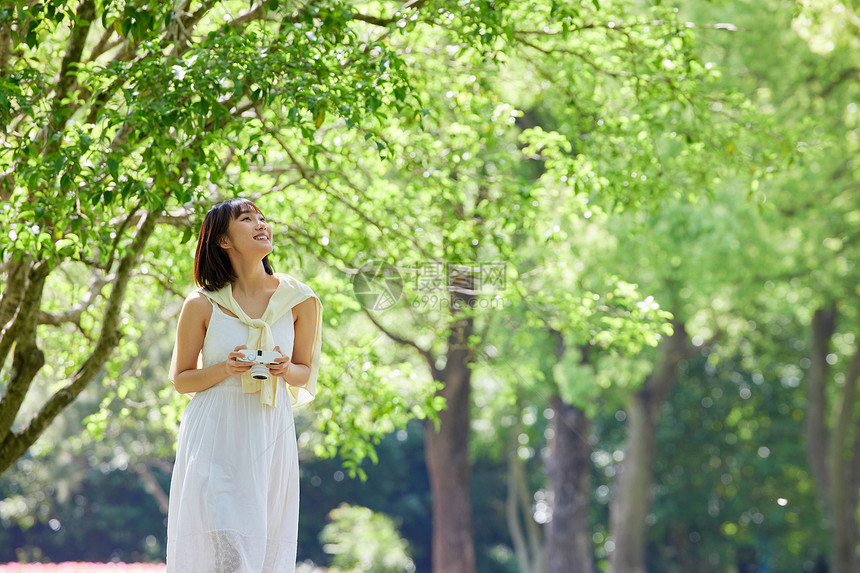 手拿照相机在公园散步的女孩图片