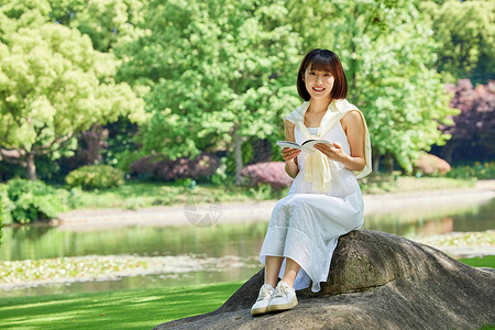 河边的少女女生夏日坐在河边石头上看书形象背景