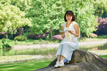 女生夏日坐在河边石头上看书形象图片