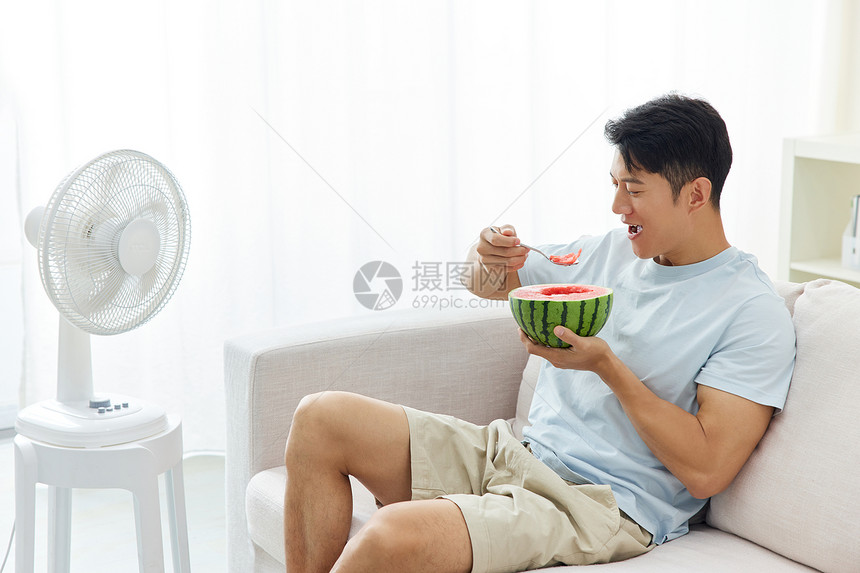 男人靠在沙发上吃西瓜吹风扇图片