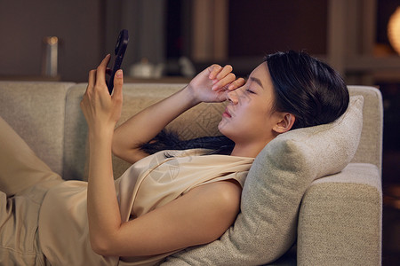 居家休息躺在沙发上玩手机眼睛不适的女性形象背景