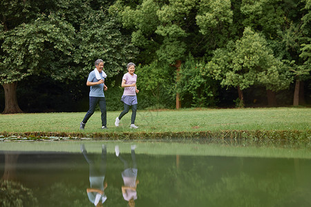 河边草坪上跑步的老夫妻高清图片