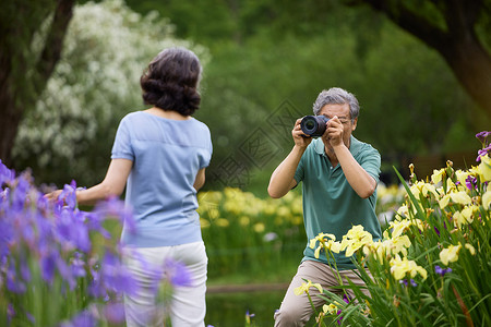 老爷爷给花丛中的奶奶拍照图片