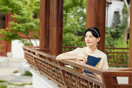 旗袍女性庭院中读书背景图片