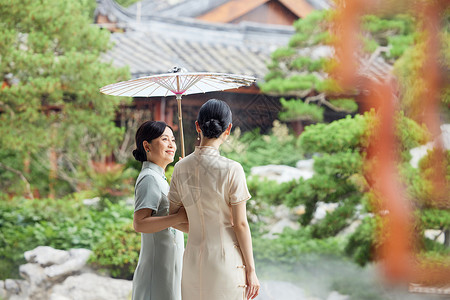 下雨天在中式庭院撑伞的旗袍母女背景图片