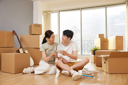 纸箱子情侣在新家地板上玩手机形象背景