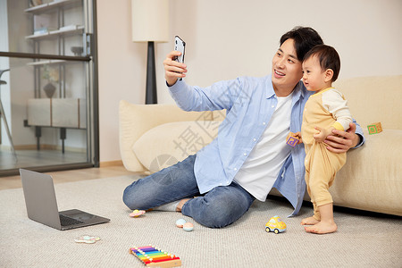年轻父亲使用手机和宝宝合照图片