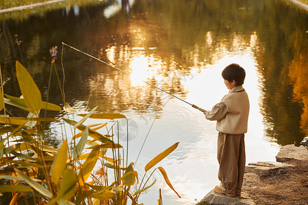 夕阳下在河边钓鱼的男孩图片