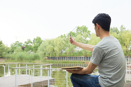 拿着调色盘和画笔绘画的男生男性在室外画风景写生素描背景