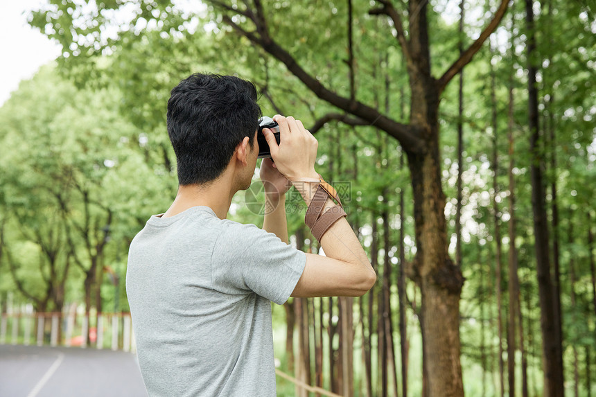 在公园手拿相机的年轻男性图片