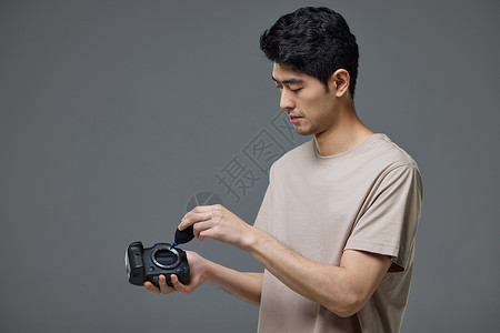 摄影师使用气吹给照相机清灰尘背景
