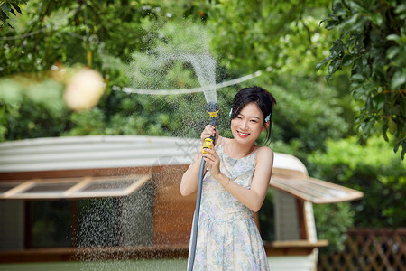 浇水的女生户外女生享受夏日浇水背景