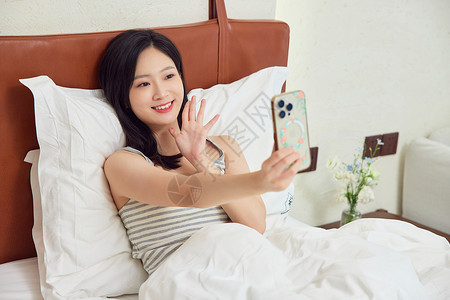 在床上玩手机的女生图片