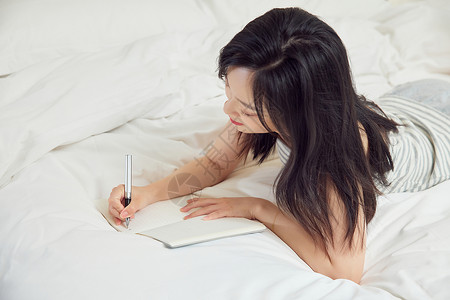 居家女生在床上写日记高清图片