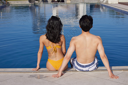 完美夏日毛笔字身材完美的情侣坐在泳池边背景