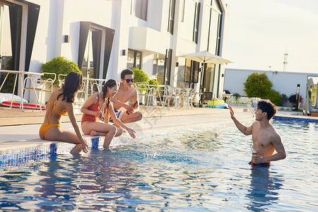 夏日情侣度假村游泳池里嬉戏玩水的年轻男女背景