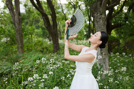 公园里舞扇子的白裙女子背景图片