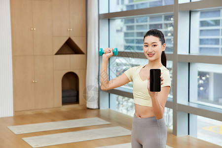 瑜伽馆锻炼的美女展示手机屏幕图片
