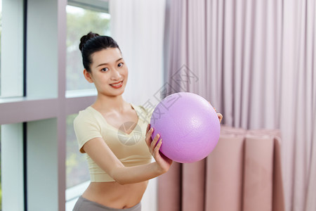 运动女生举着紫色瑜伽小球背景