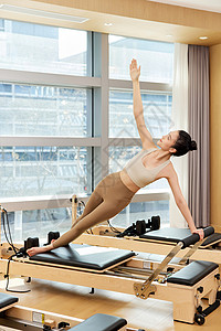 用普拉提核心床训练的运动女生背景图片