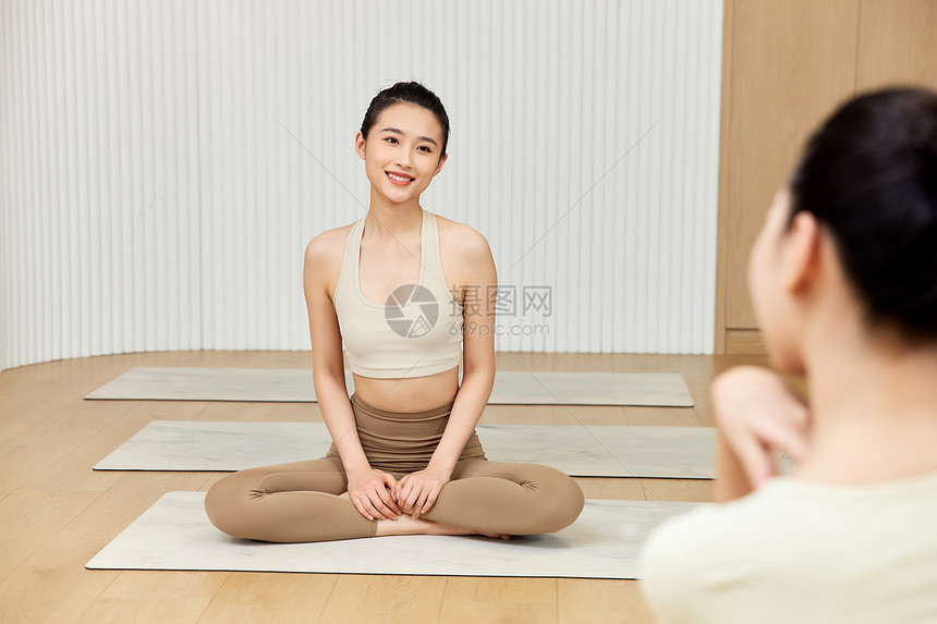 两个女生坐在瑜伽垫上聊天图片