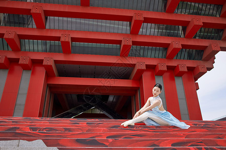 圆柱和红色阶梯阶梯上休息的女舞者背景