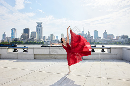 城市景色下的红裙舞者高清图片