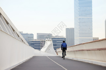 靠道路右侧骑行的男性背影高清图片