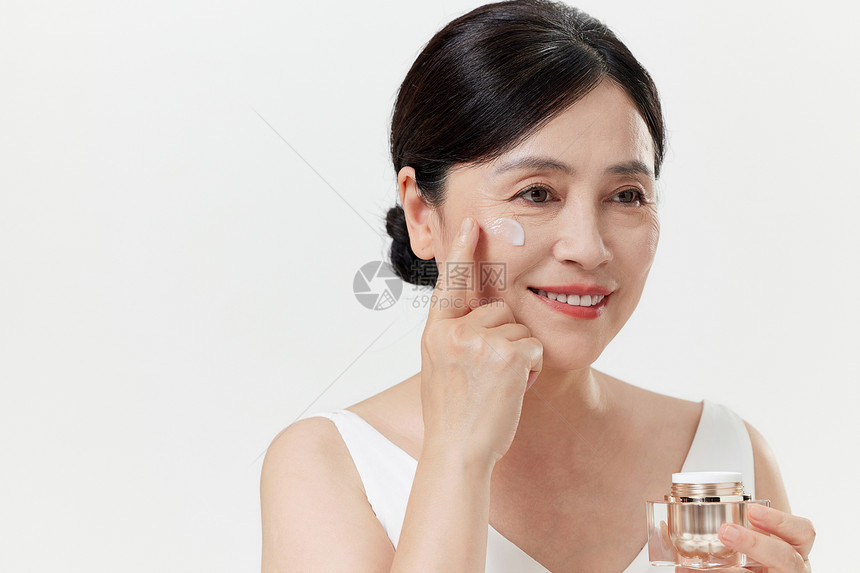 中年女性在脸上涂抹乳液图片