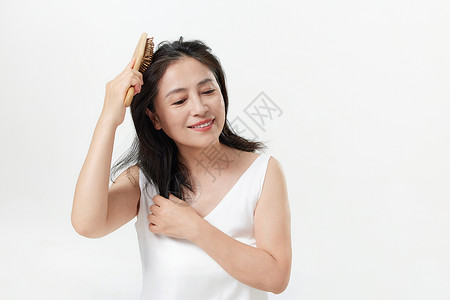 梳头发中年女性用按摩梳护理头皮背景