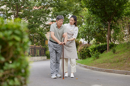 护工搀扶老年人户外散步图片