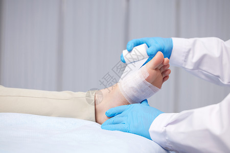 医生使用绷带包扎患者脚部特写图片