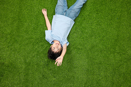 小男孩躺在草坪上打招呼高清图片