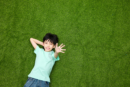 招手的男孩躺在草坪上开心招手的小男孩背景