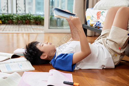 元上小学素材躺在地板上看书的男孩背景