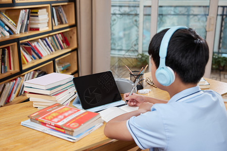 听音乐男孩戴着耳机学习在线课程的儿童背景