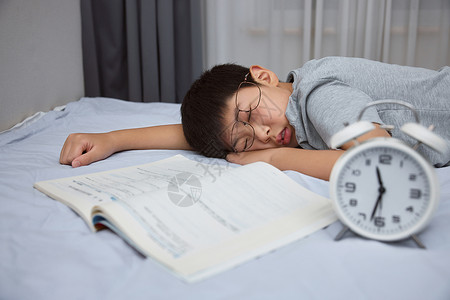 起床儿童趴在床上写作业睡着的男孩背景