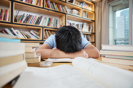 睡着的男孩疲劳学习的男孩趴在书桌上补觉背景