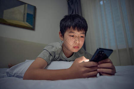 在床上熬夜玩手机的男孩背景