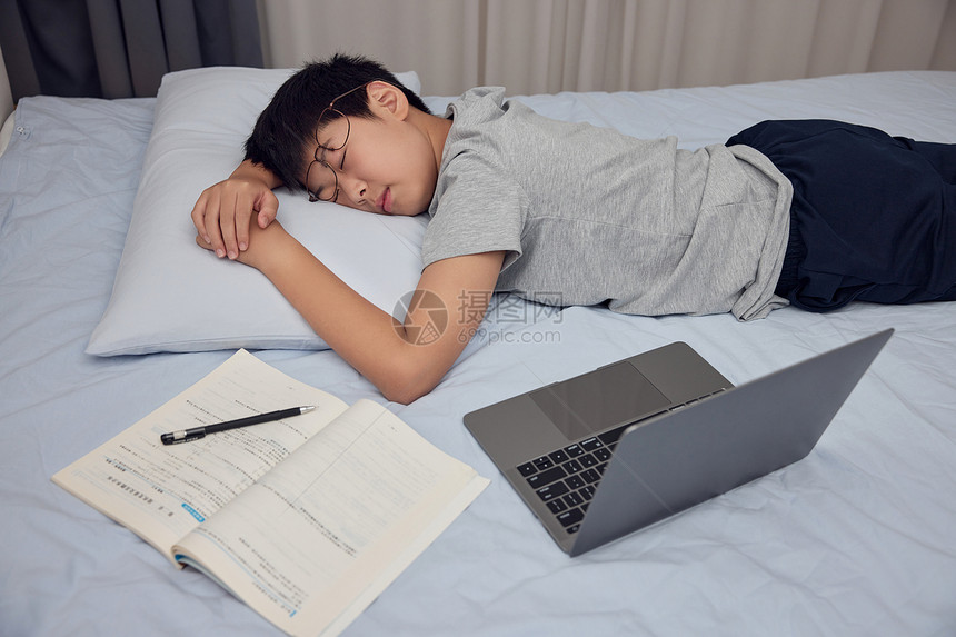 男孩熬夜做作业趴在床上睡觉图片