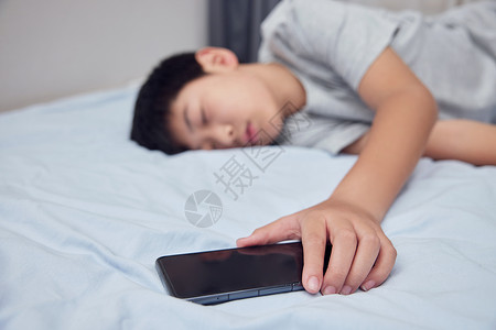 男孩在床上拿着手机睡觉图片