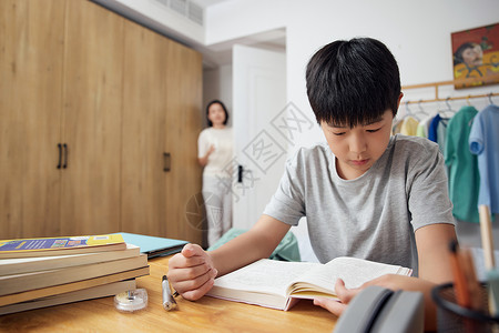 正在读书的男孩妈妈在卧室门口观察正在学习的孩子背景