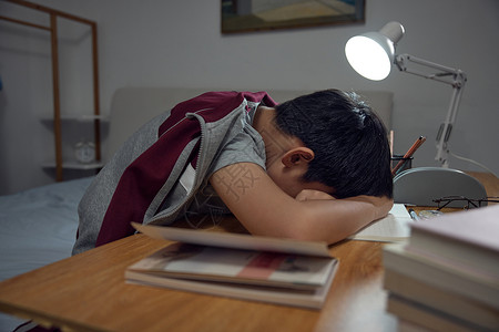 读书困趴在书桌上睡觉的男孩背景