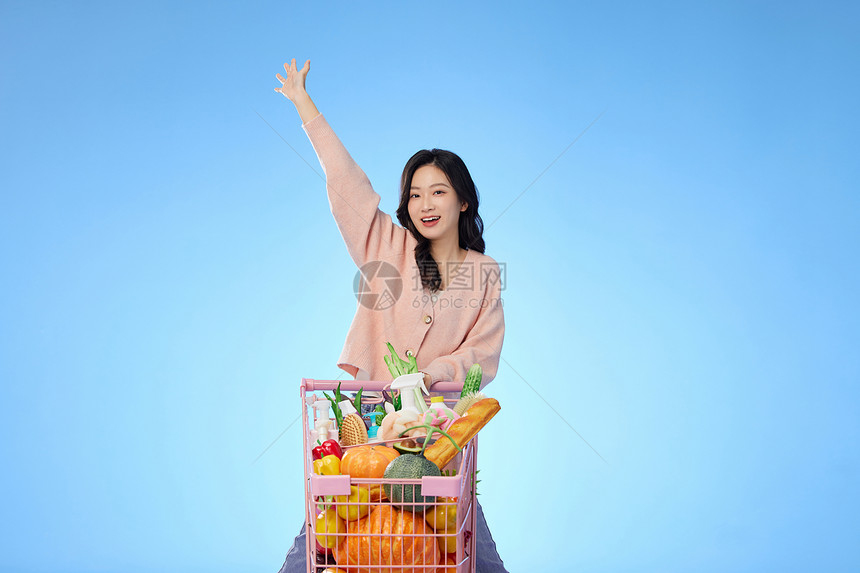 美女开心地推着装满食物的购物车图片