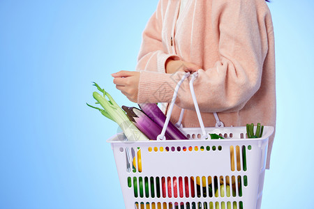 女生拿着装满蔬菜的购物篮背景图片