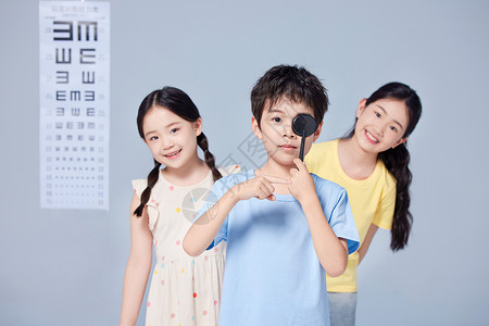 两个小女孩看着男孩做视力检测图片