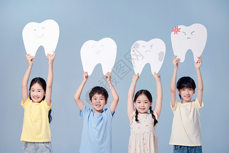 举着红枣的男孩四个小朋友高高地举着牙齿模型牌背景